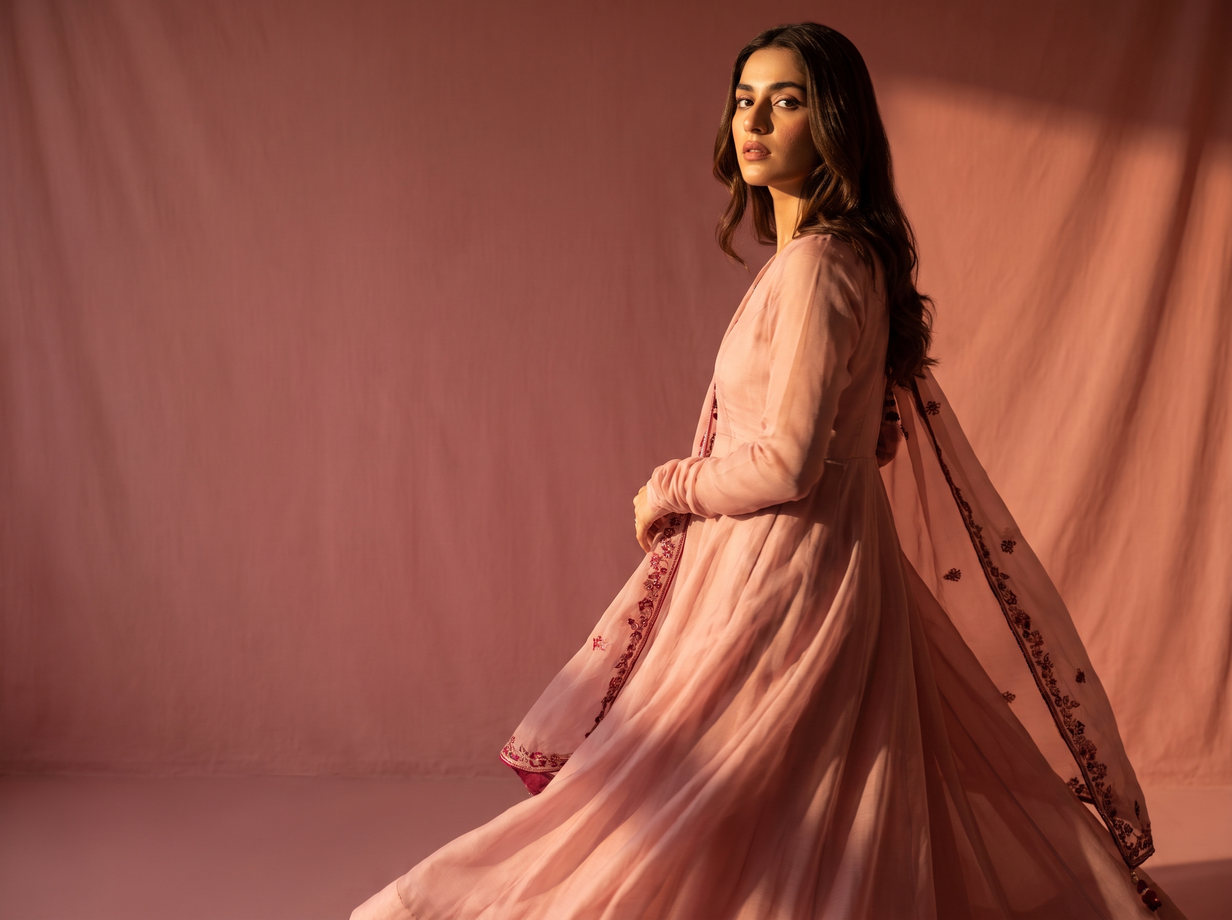 Blush lawn-weight set caught mid-turn on a rose studio backdrop